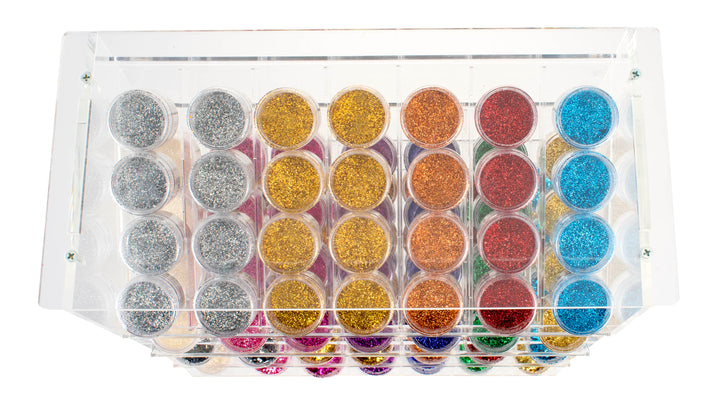 Die Draufsicht auf das Glorex Bio-Glitter Display 112tlg zeigt Reihen von kleinen Behältern mit buntem, umweltfreundlichem, biologisch abbaubarem Bio-Glitter in Silber-, Gold-, Orange-, Rot-, Blau- und Pink-Tönen.