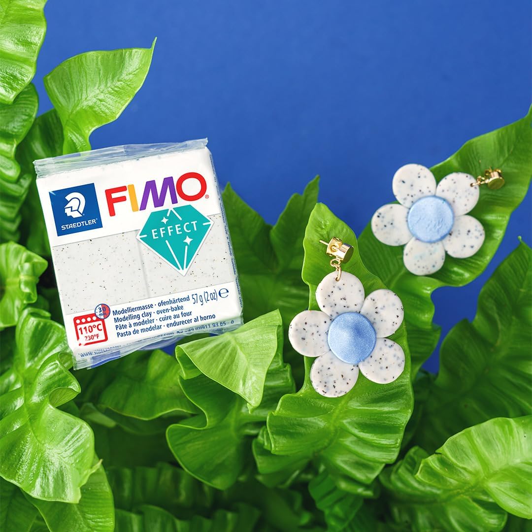 FIMO Effect Lehm neben blauen Blumen-Ohrschmuckstücken auf grünen Blättern
