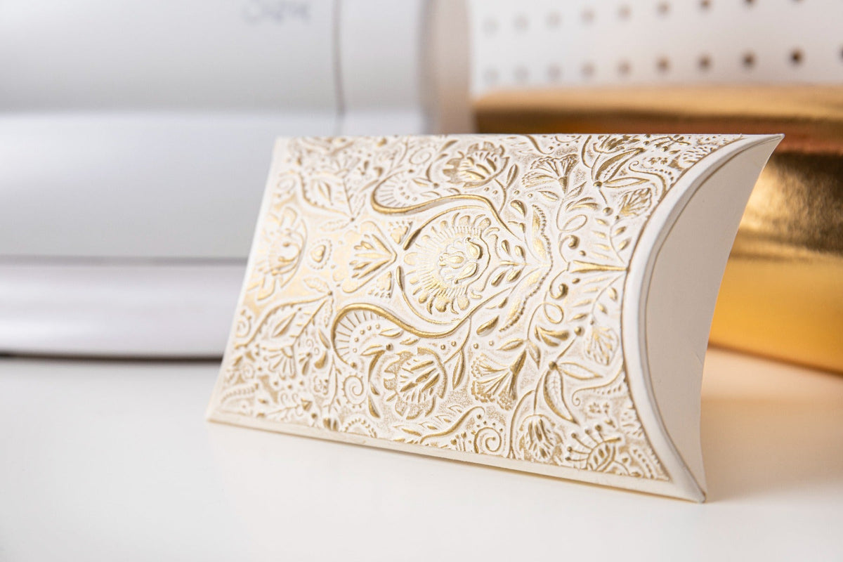 Goldenes Glanzwachs auf weißem floralen Stanzpapier mit metallischem Reflex