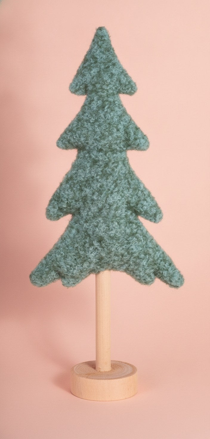 Petrolfarbener Plüschtannenbaum mit flauschiger Textur und rundem Holzsockel vor rosafarbenem Hintergrund